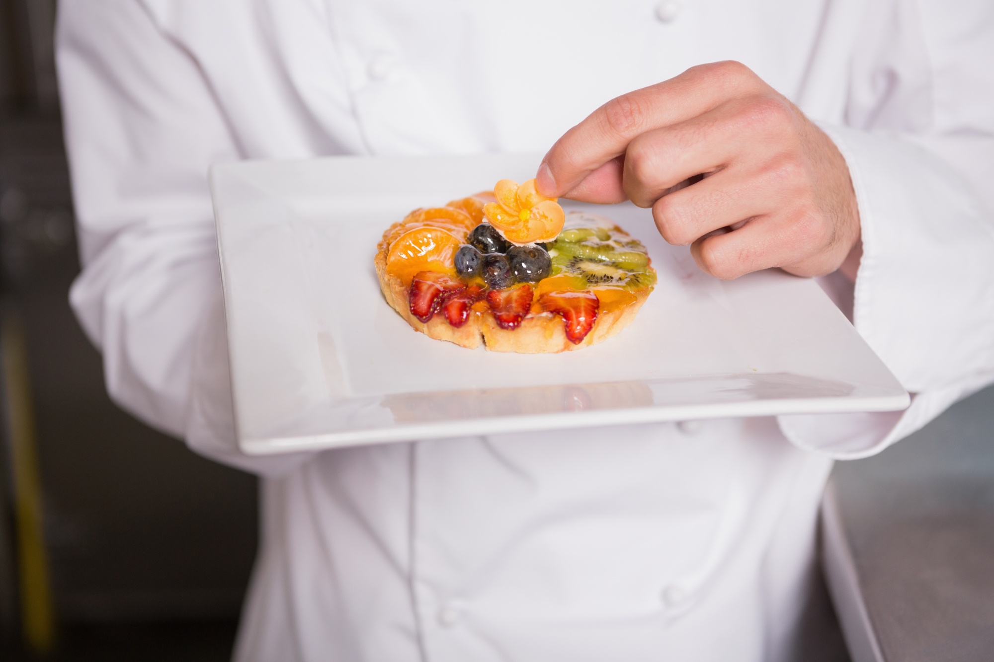 Instructor demonstrating precision plating in a tech-equipped kitchen